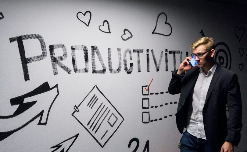 man holding smartphone looking at productivity wall decor