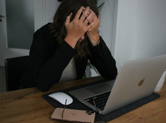 a woman covering her face while looking at a laptop